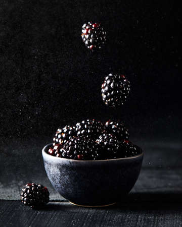 Fresh blackberry levitation on dark black background close up