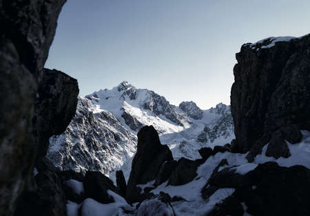 Beautiful panorama at high mountains with snow and black rocks against blue sky at winter time in Kazakhstanの写真素材