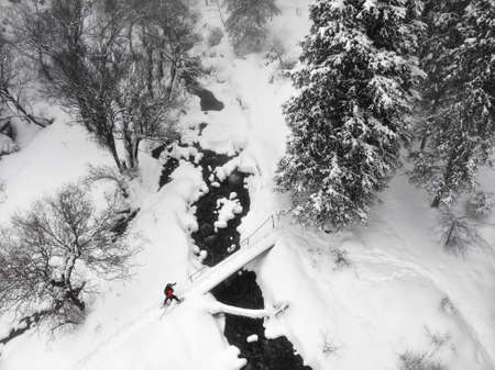 Woman climber in orange jacket with ice axe near frozen waterfall in the mountainsの写真素材