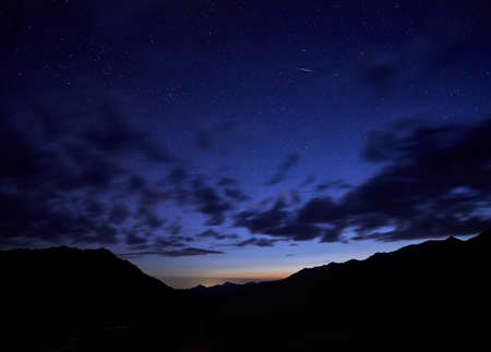 Silhouette of mountains at night cloudy sky with starsの写真素材