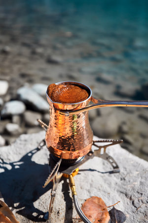 Copper Cezve for coffee in autumn lake camping in the mountains. Preparing coffee on gas stove outdoor camping conceptの写真素材