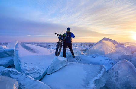 Man with fat bike on the frozen lake Kapchagay at sunset in Kazakhstanの写真素材