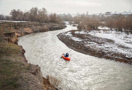Man is paddling on orange raft boat in the river at wintertime.の写真素材