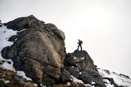 Man with backpack climbing to the summit in the beautiful mountains landscapeの写真素材