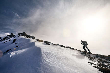 Man with backpack climbing to the summit in the beautiful mountains landscape
