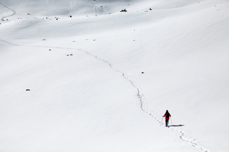 Man with backpack walking on the snow hill with footprints in Almaty, Kazakhstan