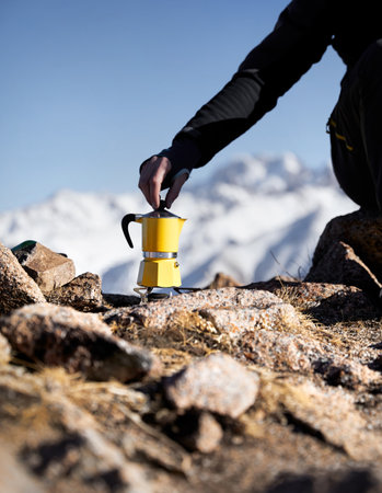 Man hiker making coffee from Yellow Moka mocha pot outdoors in the snow winter mountains. Old style coffee vintage pot outdoor campingの写真素材