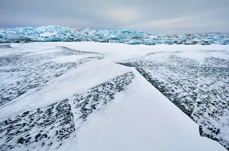Beautiful landscape of big blue peace of Ice hummock and cracks at frozen lake with snowの写真素材