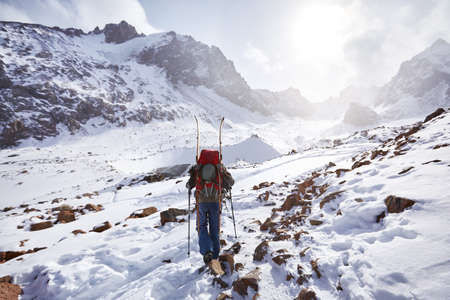 Skier man climbing with split board in high snowy mountains. Sport outdoor winter season.の写真素材