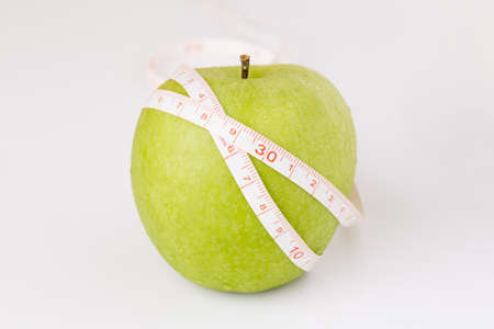 White tape measuring wrapped around green appleの写真素材