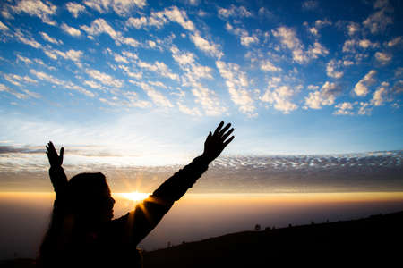 Girl silhouette with open arms freedom feeling over sunrise backgroundの写真素材