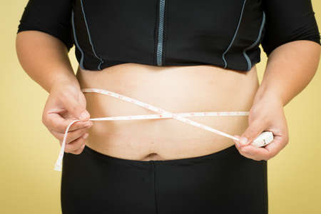 fat woman measuring her stomachの写真素材