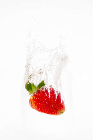 Red strawberry inside flowing water on white backgroundの写真素材