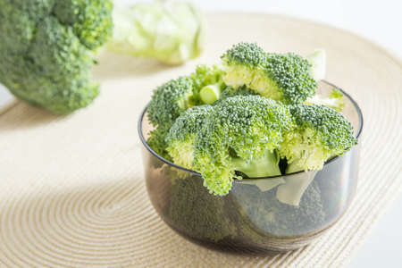 Bunch of fresh green broccoli on brown plate over bamboo backgroundの写真素材