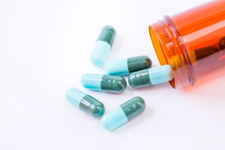 Blue pills an pill bottle on white background