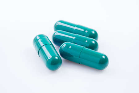 Capsules of green herbal supplement product isolated on white backgroundの写真素材
