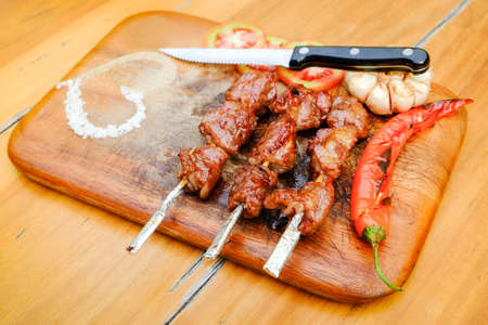 delicious grilled meat  with vegetables and pepper and salt on a wooden surfaceの写真素材