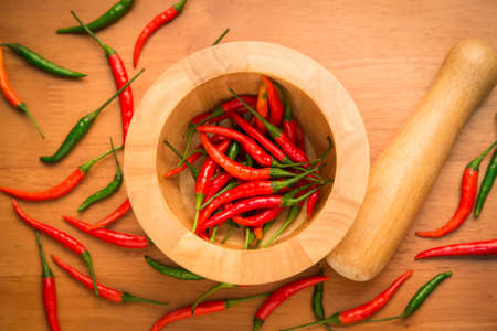 Chillies in Mortar with Pestle on wooden backgroundの写真素材