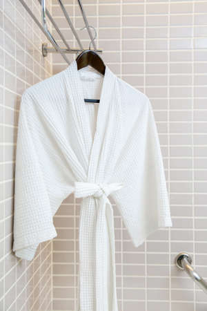 White bathrobe on hanger with mosaic tiles backgroundの写真素材