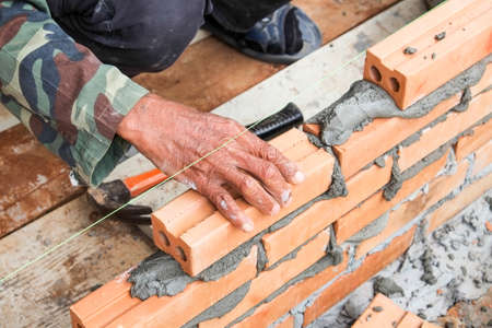 worker working on wet layer concrete, brick wall