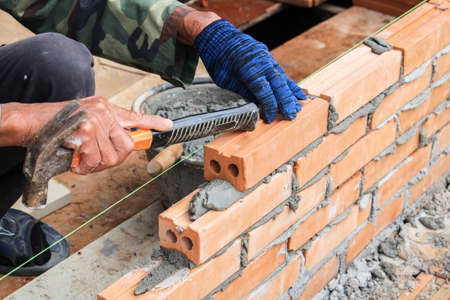 worker working on wet layer concrete, brick wall