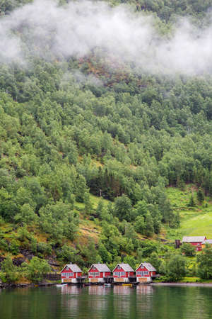 Red wooden docks in small tourist town of Flam on western side of Norway deep in fjords. Forest Backgroundの写真素材