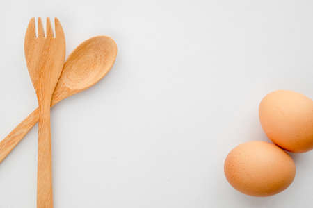wooden fork and spoon with two egg on white background