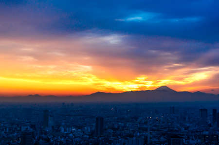 The sun sets over the cityscape of Tokyo, with Mount Fuji in the far distance view from Mori tower , roppongi hills , tokyoの写真素材