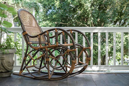 An old wooden rocking chair sitting outside on a dirty front porchの写真素材