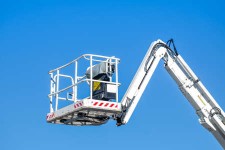 Bucket truck high up of a crane with blue skyの写真素材