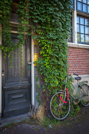 Old rusty bicycle  leaning against house wallの写真素材