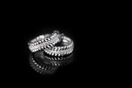 A couple of diamond earrings isolated on Black with reflectionの写真素材