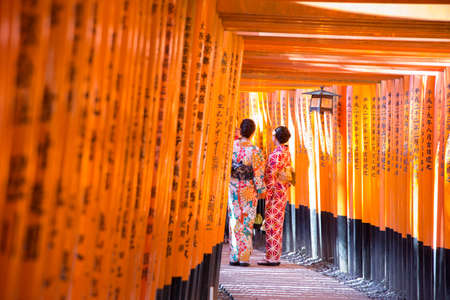 women geishas among red wooden Tori Gate at Fushimi Inari Shrine in Kyoto, Japanのeditorial素材