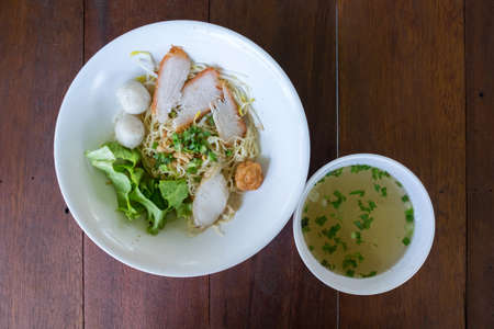 Thai Noodles "Kuay Tiew " with pork and fish meat ball and vegetables with soup on wooden tableの写真素材