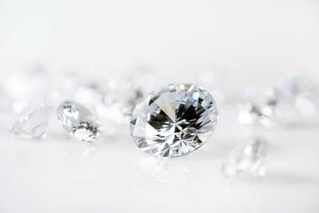 brilliant cut diamond held by tweezers on white backgroundの写真素材