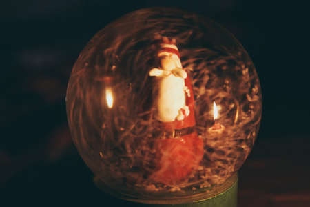 Snowy glass ball with Santa Claus inside, which reflects the burning candleの写真素材