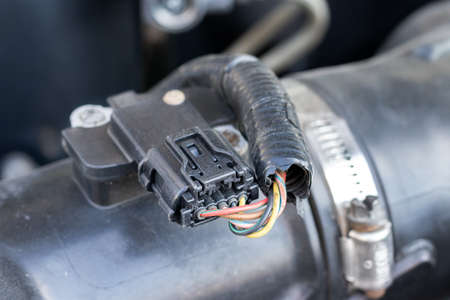 Mass air flow (MAF) sensor under the open hood of a car - measures the air flow in the engine to give the correct readings on the engine control unit (ECU) to adjust the fuel-air mixtureの写真素材