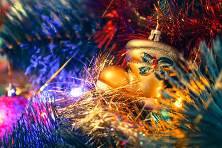 Golden boot toy hanging on a Christmas tree among the shiny garlandsの写真素材