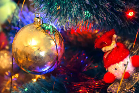Golden ball and knitted toy hang on a Christmas treeの写真素材