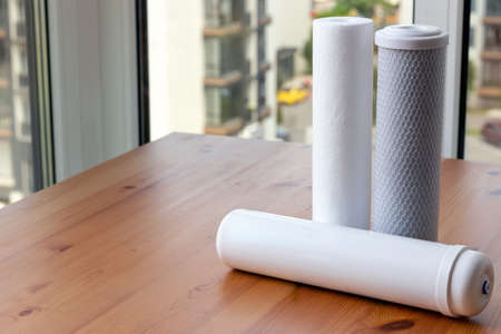 Filter cartridges for drinking water purification for on a wooden table against a blurred background with copy space. Water filtration RO (reverse osmosis) systemの写真素材