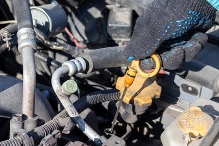 Man checking oil level under the open hood of a flat-four (boxer) car engine compartment. Closeup viewの写真素材