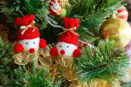Green artificial Christmas tree decorated with two beautiful snowmen on sticks with red noses and hats, and other toys for a family holidayの写真素材