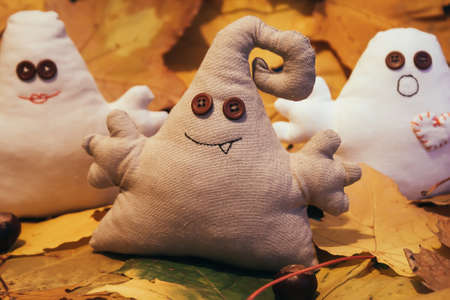 Three toy monsters with button eyes sit among leavesの写真素材