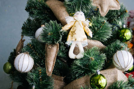 Artificial Christmas tree in rustic style, decorated with white and green balls, sackcloth toys and an angel toyの写真素材