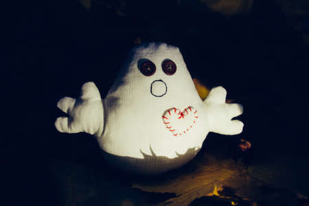A toy monster with button eyes sits in the darkの写真素材
