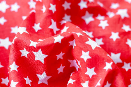 Red fabric texture with printed white stars. Crumpled bright colored cotton background. Selective focus. Closeup viewの写真素材