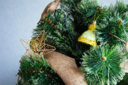 Artificial Christmas tree in rustic style, decorated with green hat toy, sackcloth toys and a golden starの写真素材
