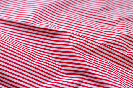 Red and white striped fabric texture. Crumpled bright colored cotton background. Selective focus. Closeup viewの写真素材