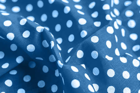 Classic blue polka dot fabric texture. Crumpled bright colored cotton with printed white circles background. Selective focus. Closeup viewの写真素材