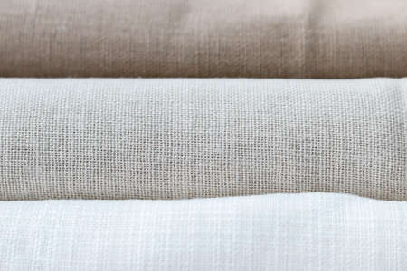 Horizontal textural background of three types of natural linen fabric, rolled up. Selective focus. Closeup viewの写真素材
